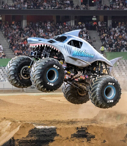 Monster Jam truck performing inside a South African stadium with dirt ramps and production lighting